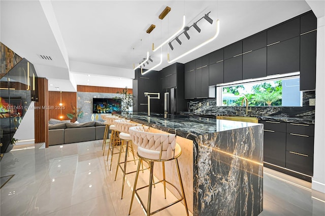 kitchen with a breakfast bar, tasteful backsplash, hanging light fixtures, dark stone countertops, and wooden walls