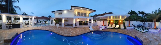 back house at dusk featuring a fenced in pool, a patio, and ceiling fan