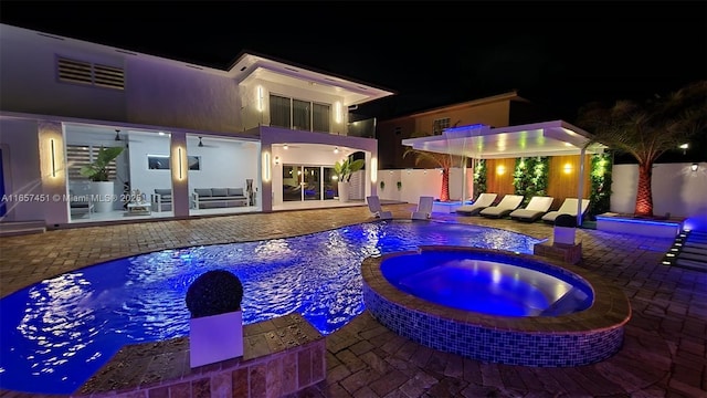 pool at twilight featuring a patio and an in ground hot tub