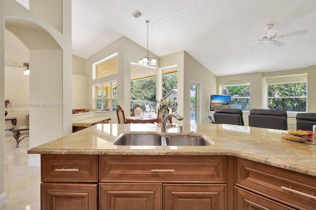 kitchen with a healthy amount of sunlight, ceiling fan with notable chandelier, vaulted ceiling, and sink