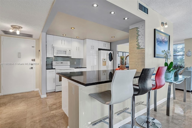 kitchen with white cabinetry, a textured ceiling, white appliances, tasteful backsplash, and a breakfast bar