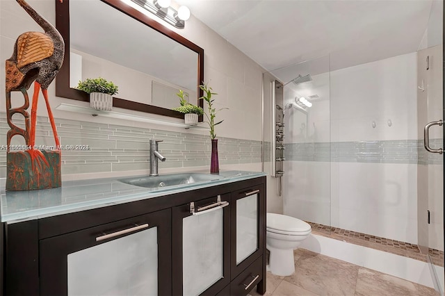 bathroom with toilet, tile patterned flooring, vanity, tasteful backsplash, and a shower with shower door