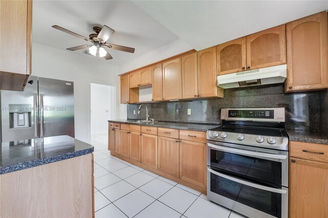 kitchen featuring dark stone countertops, tasteful backsplash, sink, ceiling fan, and appliances with stainless steel finishes