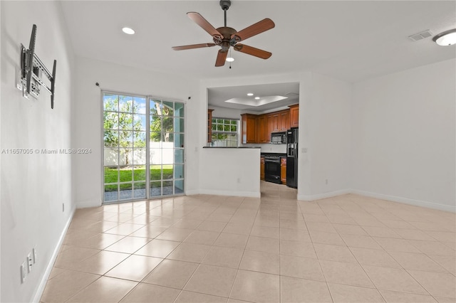 unfurnished living room featuring ceiling fan, light tile patterned flooring, and a raised ceiling