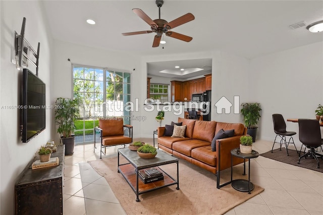 tiled living room featuring ceiling fan and a raised ceiling