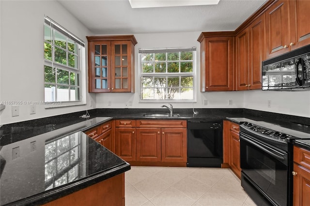 kitchen featuring dark stone counters, sink, a healthy amount of sunlight, and black appliances