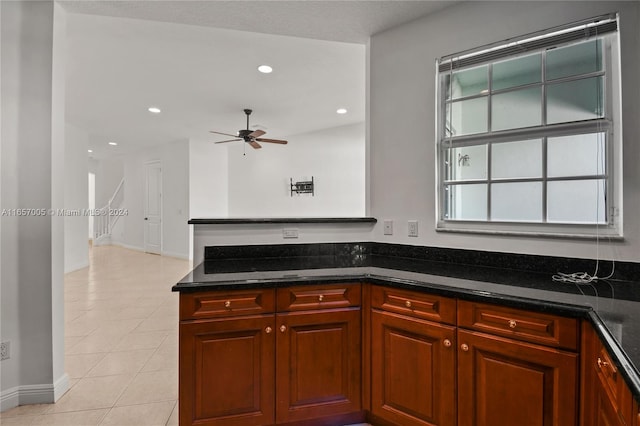 kitchen with dark stone countertops, ceiling fan, and light tile patterned floors