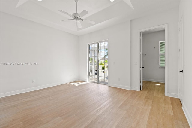 interior space with light hardwood / wood-style flooring, a tray ceiling, and ceiling fan