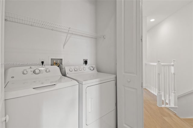 clothes washing area with washing machine and clothes dryer and light hardwood / wood-style flooring