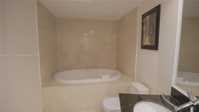 bathroom featuring vanity, tiled tub, and toilet