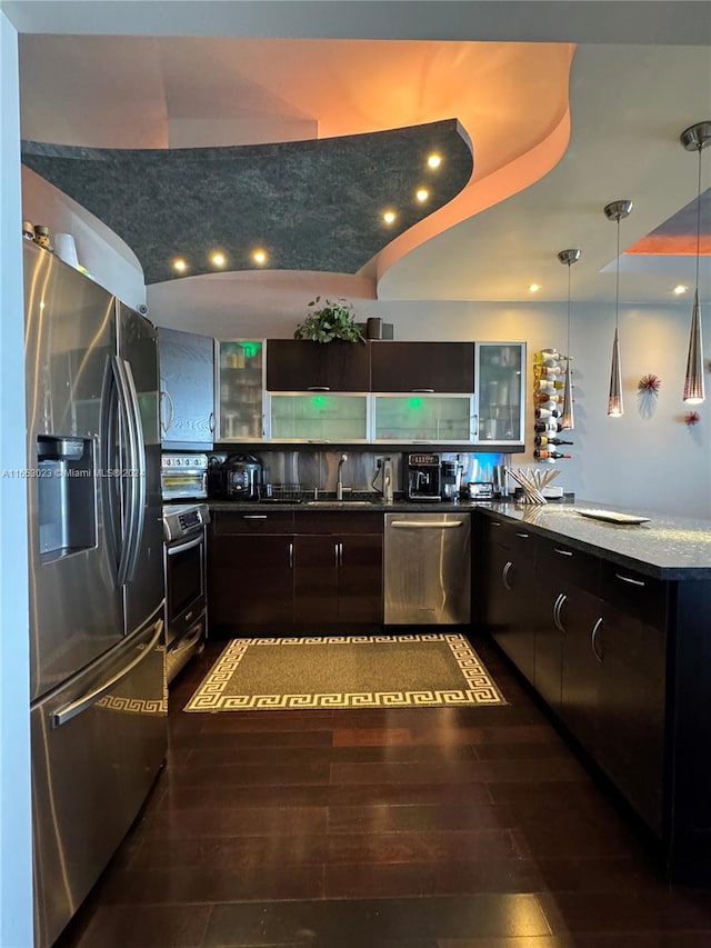 kitchen featuring hanging light fixtures, hardwood / wood-style flooring, stainless steel appliances, sink, and dark brown cabinets