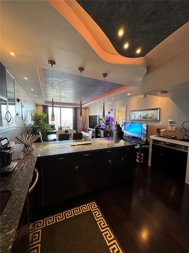 kitchen featuring dark wood-type flooring, dark stone countertops, and hanging light fixtures