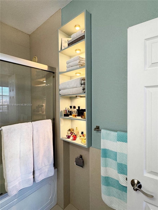 bathroom featuring a textured ceiling and a shower with shower door