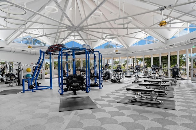 exercise room with ceiling fan and high vaulted ceiling