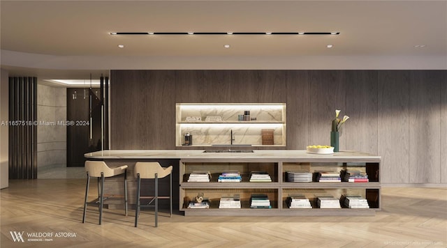 bar featuring light parquet flooring, wood walls, and sink