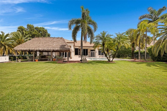 rear view of property with a gazebo, a patio area, a yard, and a pool