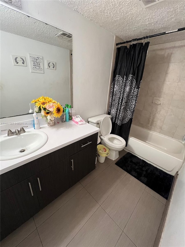 full bathroom with vanity, a textured ceiling, shower / bath combo, tile patterned flooring, and toilet