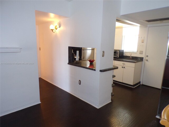 kitchen with dark hardwood / wood-style flooring, appliances with stainless steel finishes, and white cabinetry