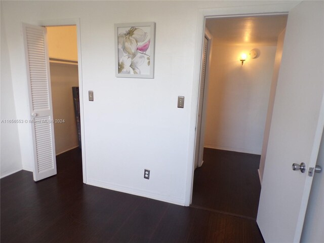 interior space featuring dark wood-type flooring, a walk in closet, and a closet