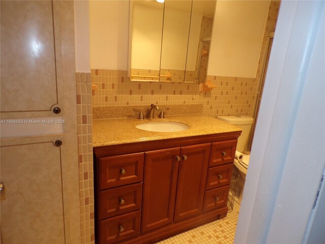 bathroom featuring vanity, toilet, tile walls, and tile patterned floors