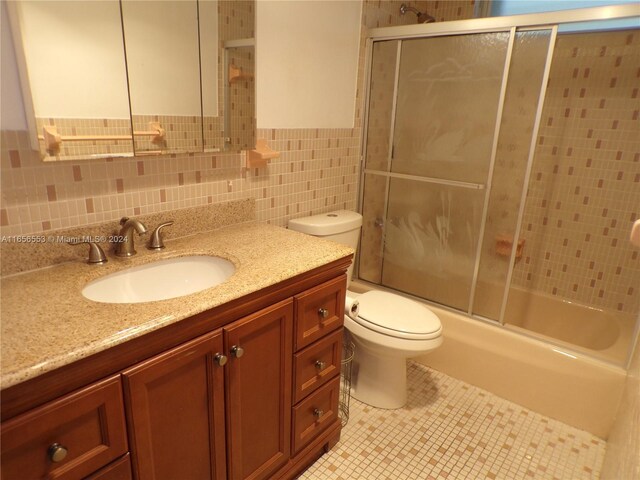 full bathroom with backsplash, toilet, combined bath / shower with glass door, tile walls, and vanity