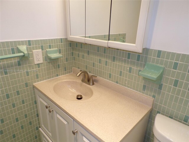 bathroom featuring tile walls, toilet, decorative backsplash, and vanity