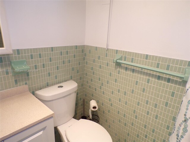 bathroom with tile walls, toilet, and vanity