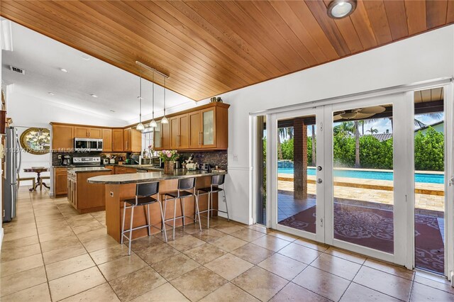 kitchen featuring pendant lighting, appliances with stainless steel finishes, backsplash, kitchen peninsula, and lofted ceiling