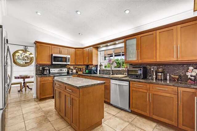 kitchen with a textured ceiling, a kitchen island, stainless steel appliances, and vaulted ceiling