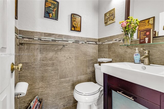 bathroom featuring tile walls, toilet, and vanity