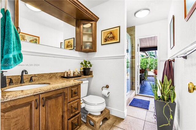 bathroom with vanity, toilet, tile patterned floors, and a shower with shower door