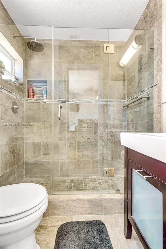 bathroom featuring tile patterned floors, walk in shower, toilet, vanity, and a textured ceiling