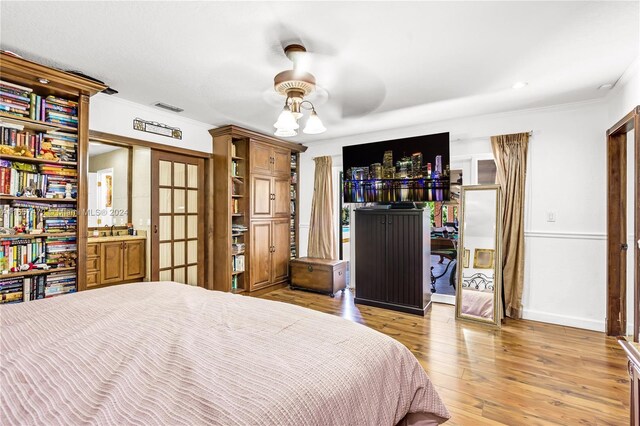 bedroom featuring light wood-type flooring, ornamental molding, and ceiling fan