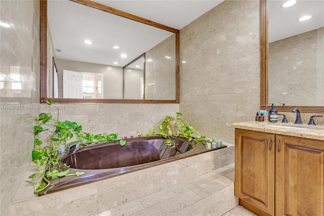 bathroom featuring vanity, tile walls, and tiled bath