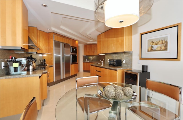 kitchen featuring built in appliances, backsplash, and stone counters