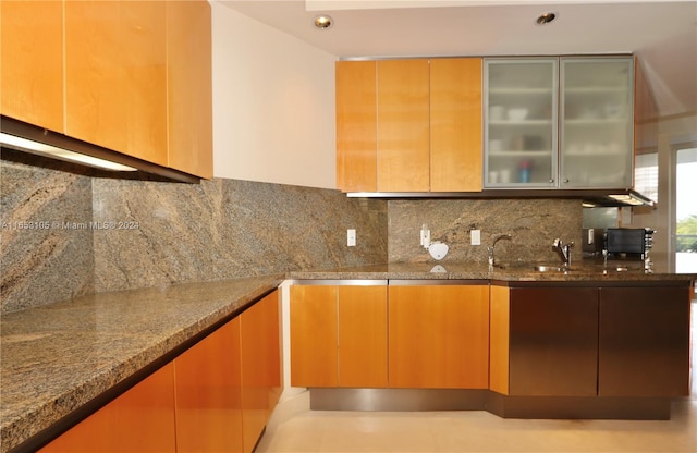 kitchen featuring stone countertops, sink, and decorative backsplash