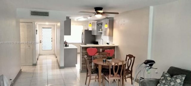 kitchen with ceiling fan, sink, light tile patterned flooring, and stainless steel refrigerator