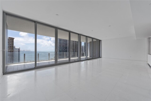 spare room featuring floor to ceiling windows and a water view