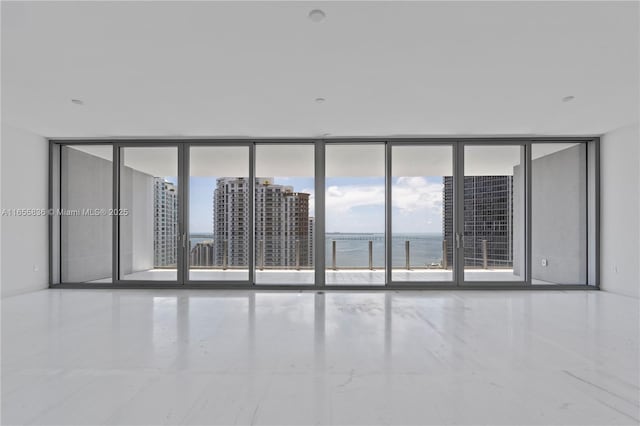 unfurnished room with floor to ceiling windows, a water view, and a healthy amount of sunlight