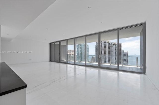 empty room featuring floor to ceiling windows, a water view, and a healthy amount of sunlight