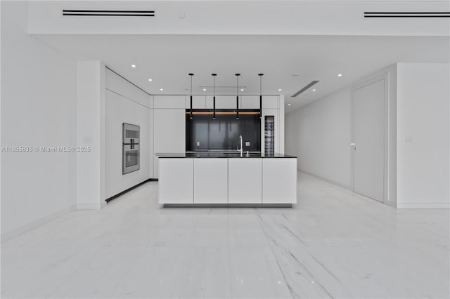 kitchen featuring white cabinetry, hanging light fixtures, double oven, and sink