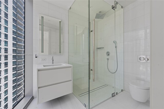 bathroom with vanity, a shower with door, tile walls, and toilet