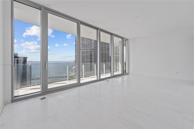 unfurnished room featuring plenty of natural light, expansive windows, and a water view