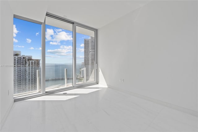 unfurnished room with a wealth of natural light, a water view, and a wall of windows