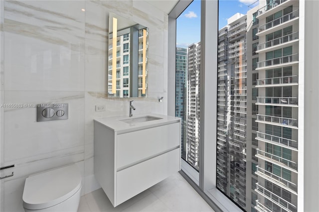 bathroom with vanity, toilet, tile walls, and tile patterned floors