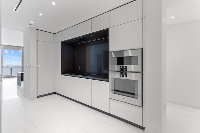 kitchen featuring double oven, black electric cooktop, and white cabinetry