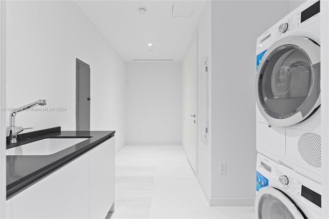 washroom featuring light tile patterned floors, cabinets, stacked washer / drying machine, and sink