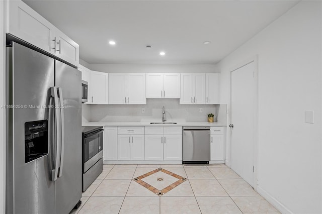 kitchen with appliances with stainless steel finishes, white cabinetry, light tile patterned flooring, and sink