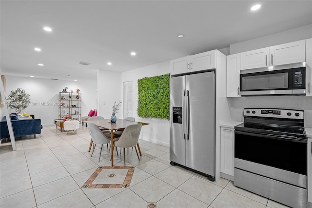 kitchen with white cabinets, stainless steel appliances, and light tile patterned flooring