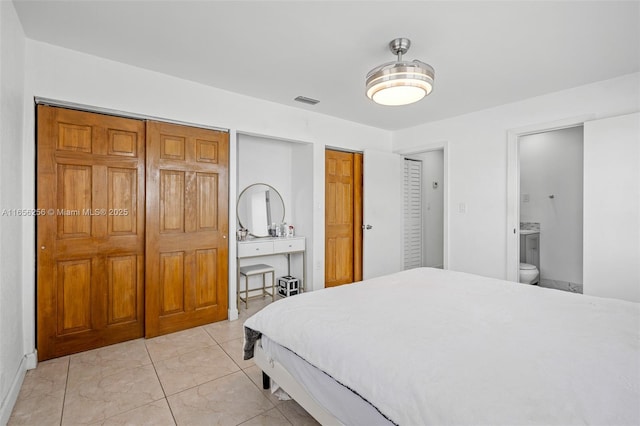 bedroom featuring ensuite bath and multiple closets